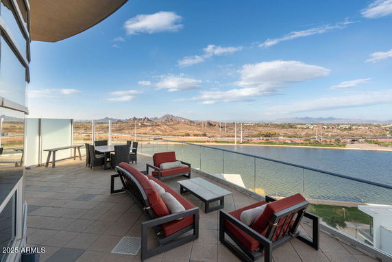 Outdoor terrace with seating area offering a panoramic view of a river and distant mountains.