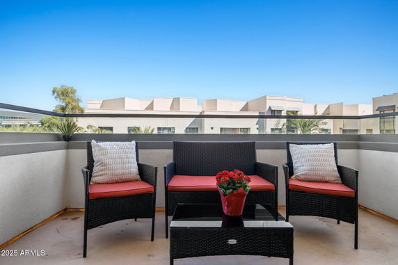 Outdoor seating area with rattan furniture and surrounding buildings in view.