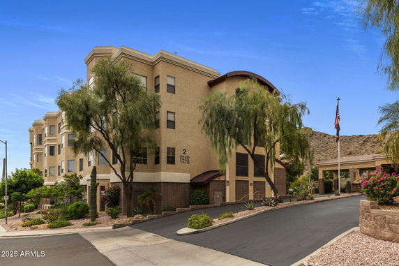 Front view of a multi-story building with a beige exterior and landscaped surroundings.