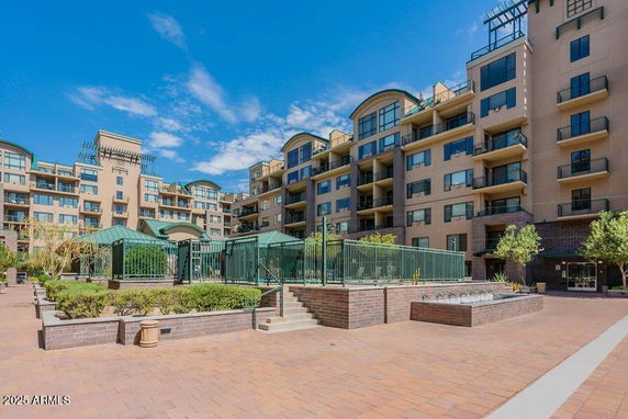 Front view of a multi-story apartment building with balconies and a courtyard.