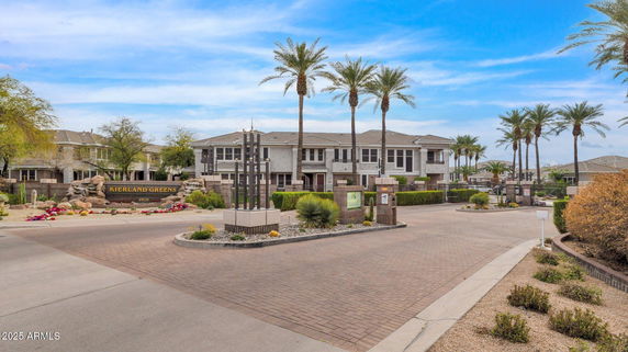 Front view of a residential complex with palm trees and gated entrance.