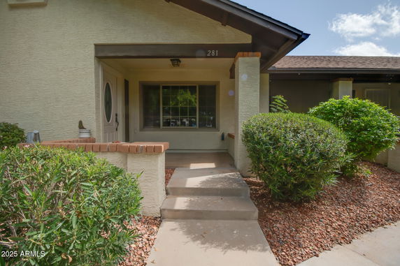 Front view of a house entrance with steps leading up and shrubbery on either side.