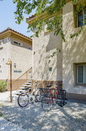Side view of a two-story stucco building with exterior stairs and windows.