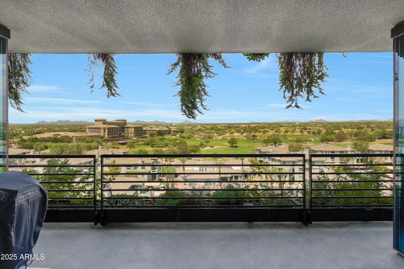 Panoramic view from a balcony overlooking buildings and a landscaped area.