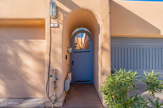 Front view of an entrance with an arched gate and adjacent garage doors.
