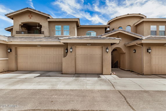 Front view of a multi-story house with garages and a balcony.