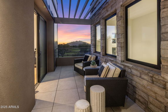 Outdoor seating area with a panoramic view of sunset and mountains.