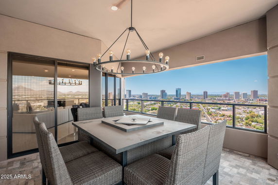 Panoramic view from a high-rise balcony overlooking a cityscape with a table setup.