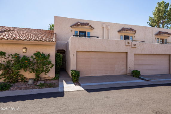Front view of a beige two-story house with a double garage and tiled roof.