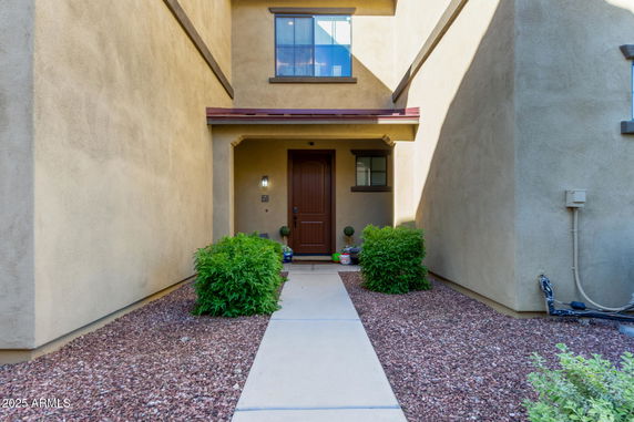 Front view of a two-story house entrance with a covered walkway and brown wooden door.