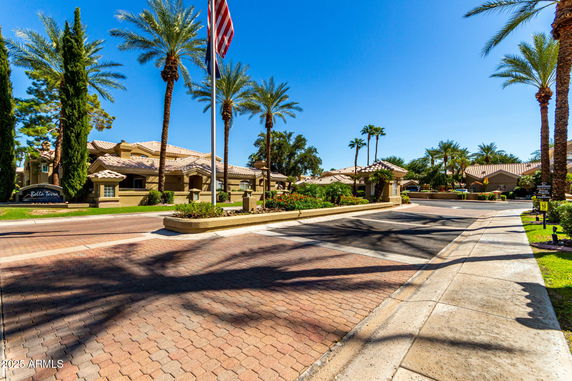 Front view of a multi-story residential complex with palm trees and a paved driveway.