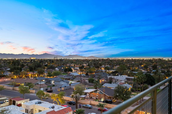 Panoramic view of a residential area at dusk with mountains in the background.