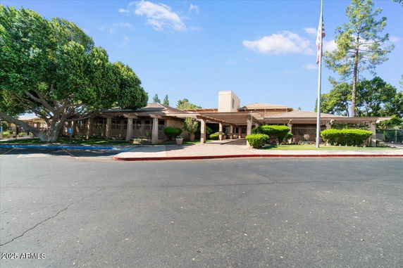 Front view of a single-story building with a covered entrance and flagpole.