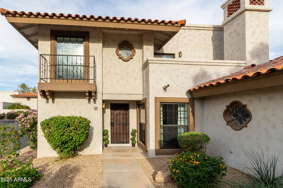 Front view of a two-story house with a small balcony and decorative windows.