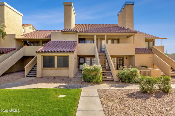 Front view of a multi-story residential building with outdoor stairs and a tiled roof.