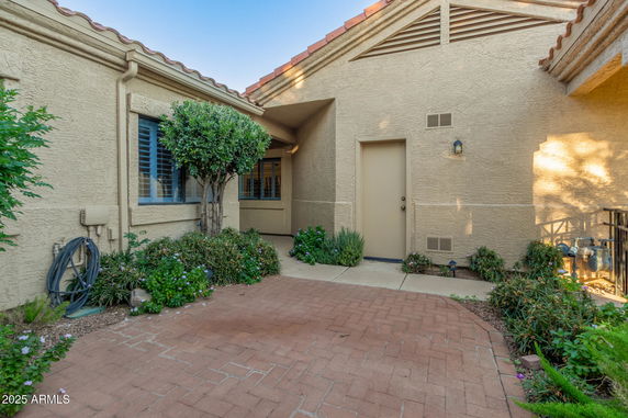 Front view of a single-story house with beige stucco walls and a tiled roof.