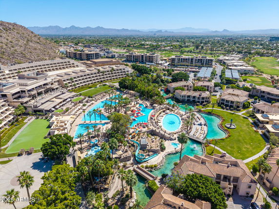 Panoramic view of a luxury resort with multiple swimming pools and surrounding buildings.