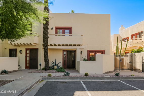 Front view of a two-story house with a modern design and gated courtyard.