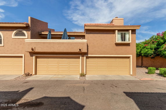 Front view of a stucco house with double garage and balcony.