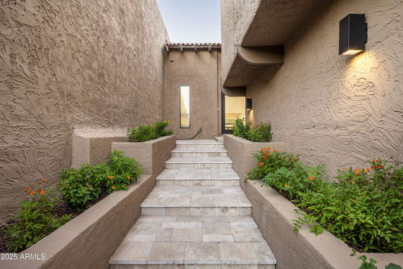 Front entrance of a building with stone steps and decorative plants.