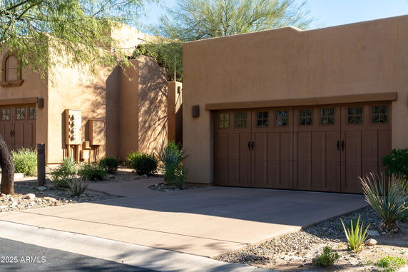 Front view of a house with a wooden garage door and stucco finish.
