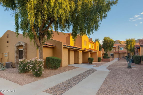 Row of two-story houses with stucco exteriors and flat roofs in a residential area.