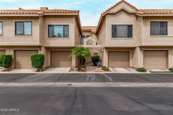 Front view of a multi-unit townhouse with attached garages and tile roofing.