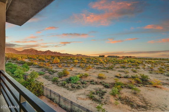Panoramic view of desert landscape and mountains from a building's balcony.