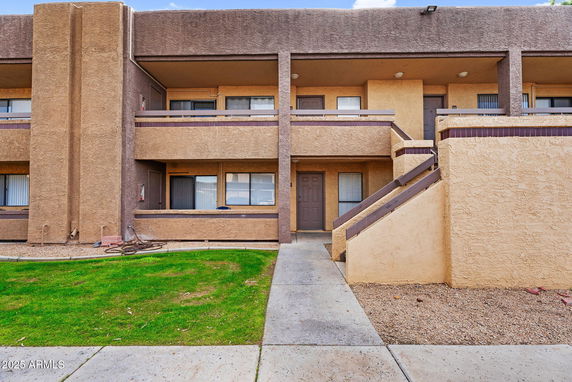Front view of a two-story building with a stucco exterior and staircase leading to the upper level.