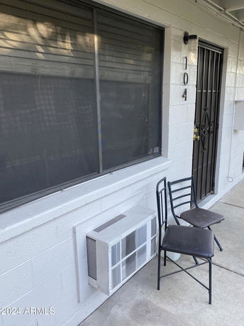 Front view of a building with a window, door, and air conditioning unit.