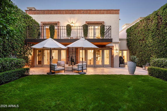 Front view of a two-story house with a balcony and patio seating.