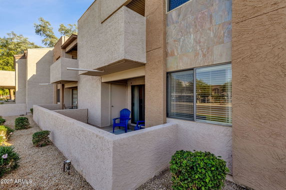Front view of a multi-story building with balconies and a small patio area.