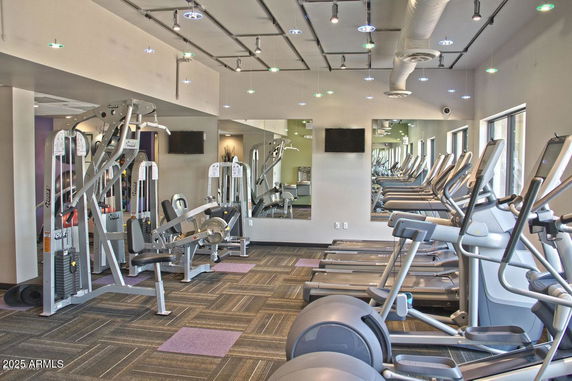 Interior view of a gym with exercise equipment including treadmills and weight machines.