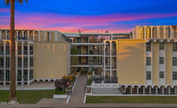 Front view of a multi-story building with arched architectural features and balconies.