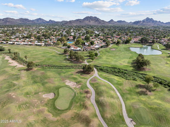 Panoramic view of a golf course with surrounding residential area and mountains