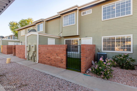 Front view of a two-story residential building with green siding and a small gated front area.