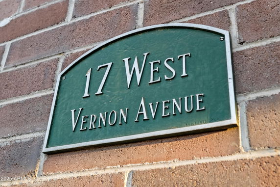 View of a building's brick exterior with a green address plaque reading '17 West Vernon Avenue'.