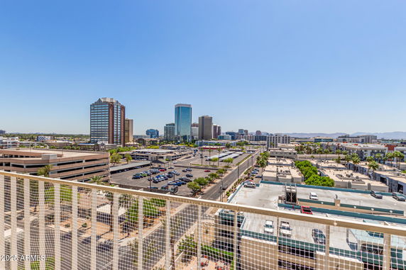 Panoramic view of a cityscape with tall buildings and a parking area.