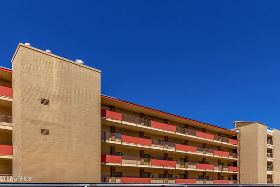 Front view of a multi-story building with balconies and a flat roof.