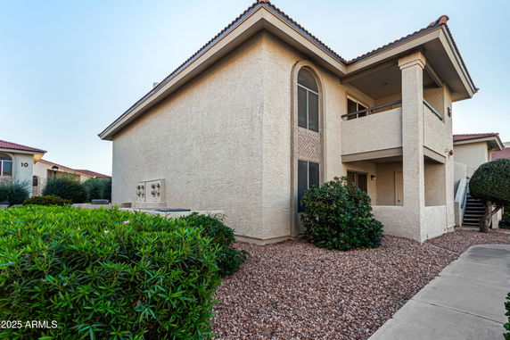 Front view of a two-story building with a balcony and desert landscaping.