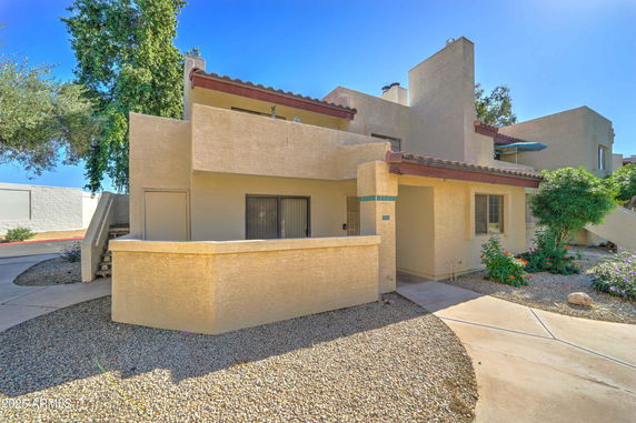 Front view of a beige two-story house with a flat roof and small balcony.