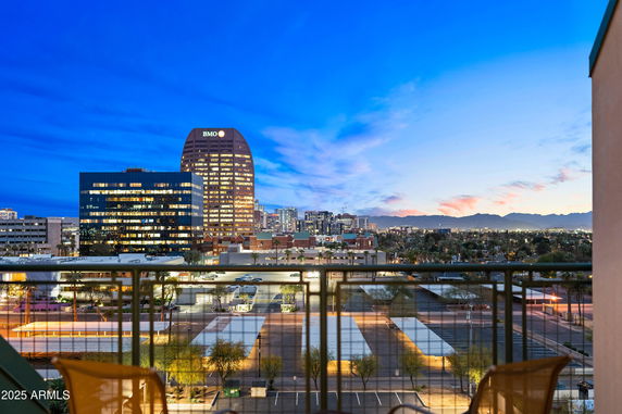 Wide view of cityscape from a balcony with buildings and mountains in the distance.