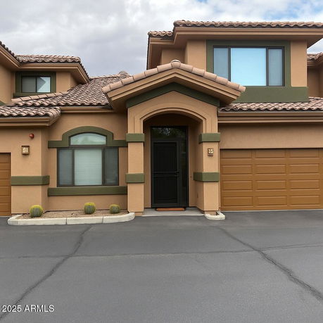 Front view of a two-story house with a tan and green exterior and attached garage.