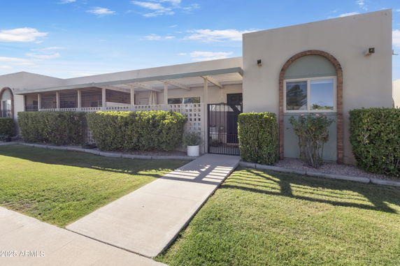 Front view of a single-story house with a covered porch and gated entrance.