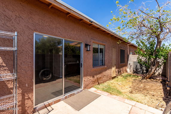 Side view of a house with stucco exterior and sliding glass door.