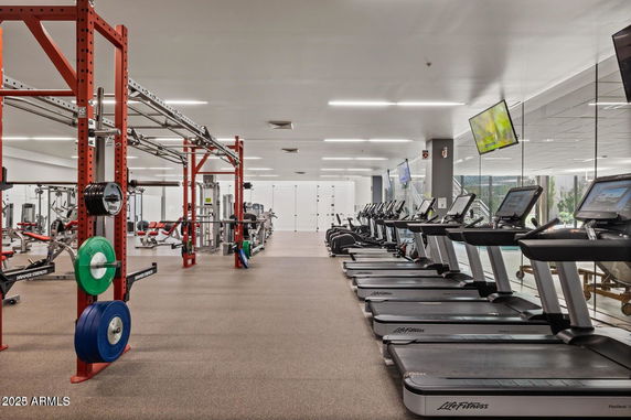 Indoor gym area with various exercise equipment including treadmills and weightlifting stations.