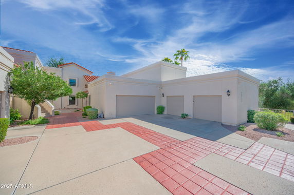Front view of a house with three garages and a red-tiled driveway.