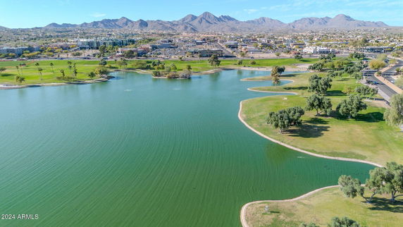 Panoramic view of a lake with surrounding greenery and distant mountains.