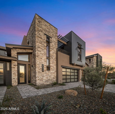 Front view of a modern two-story house with stone and metal facade.