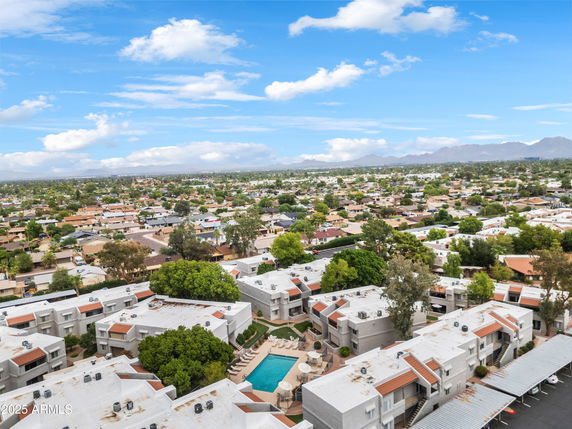 Wide aerial view of a suburban area with multiple residential buildings and a swimming pool in the center.